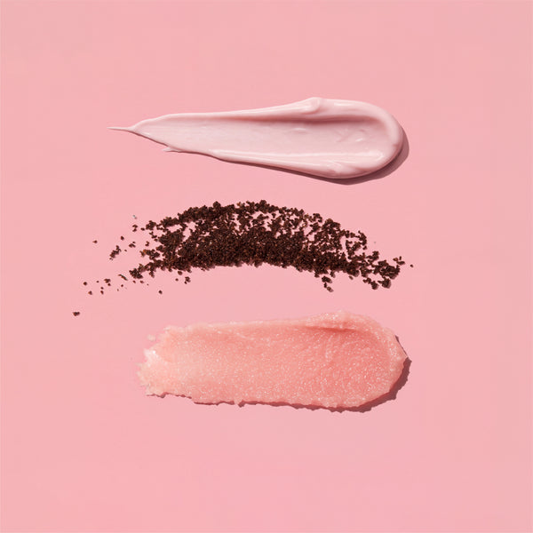 Three swatches from the frank body Baby Mama Kit on a pink background: a pink body cream, loose coffee grounds and a grainy rosehip scrub.