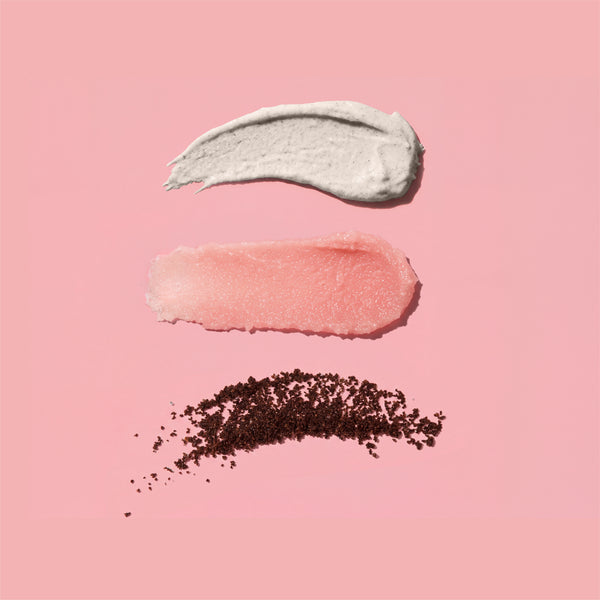 Three swatches from the frank body Scrub Stars Kit on a pink background: a white scrub, a pink scrub and a sweep of coffee grounds.