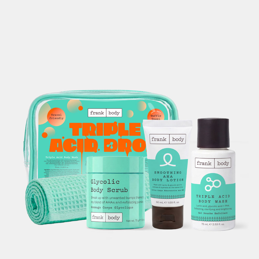 The frank body Triple Acid Drop Kit with the glycolic body scrub, AHA body lotion and body wash beside a clear mint bag and waffle towel on a white background.