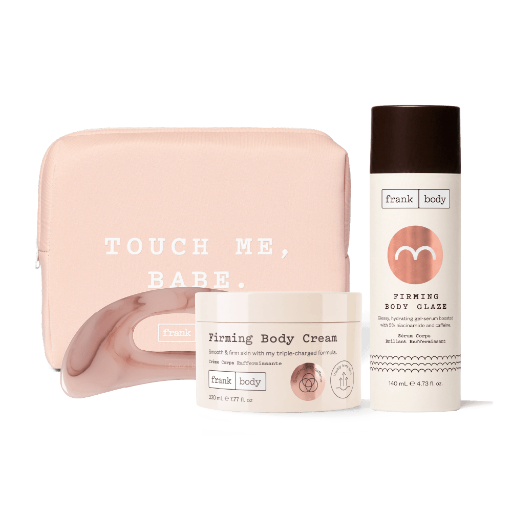 A three-piece Frank Body self-care set featuring a blush pink zippered pouch with 'TOUCH ME, BABE.' printed in white, a white jar of Firming Body Cream, and a white bottle of Firming Body Glaze with a dark brown cap, arranged on a clean white background.