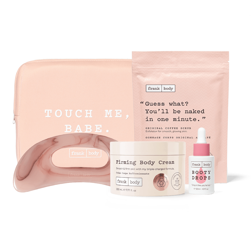 A Frank Body self-care gift set featuring a blush pink zippered pouch with the text 'TOUCH ME, BABE.', a matching pink silicone strap, a white jar of Firming Body Cream, and a white dropper bottle of Body Drops, all arranged on a clean white background.
