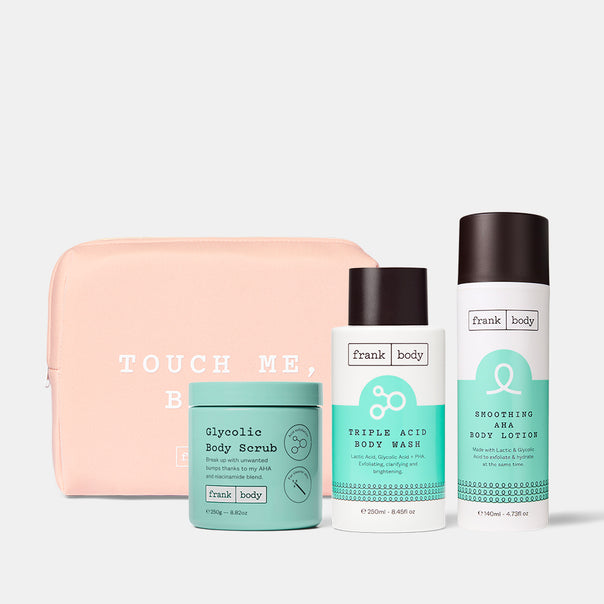 The frank body Hit the Spot Kit: Glycolic Body Scrub, Triple Acid Body Wash and Smoothing AHA Body Lotion with a pink Touch Me Babe pouch.