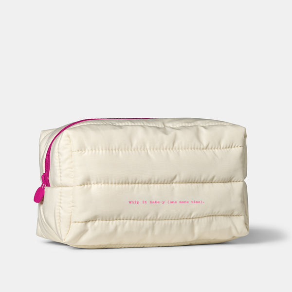 An off-white puffer-style cosmetic pouch with a bright pink zipper and small pink text on the front, photographed on a clean light gray background.