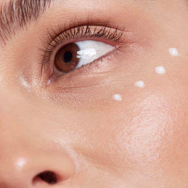 Close-up of dots of frank body Brightening Eye Serum patted under a woman's eye.